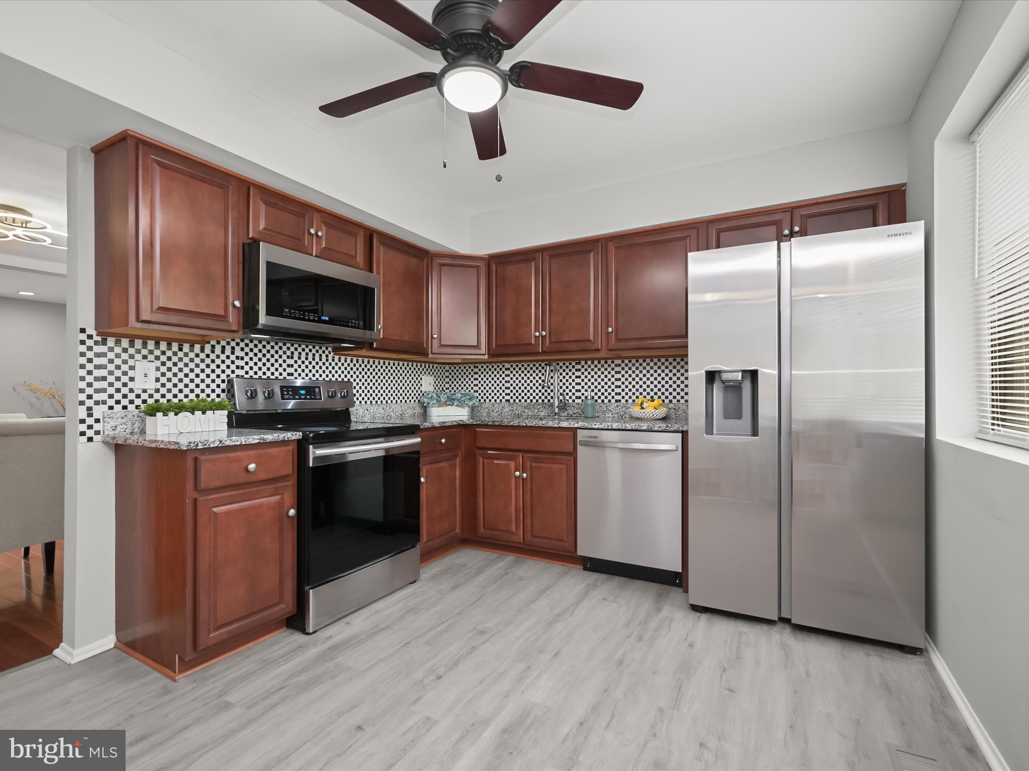 7106 Winter Rose Path Columbia, MD 21045 - Photo 8 of 50 a kitchen with granite countertop wooden floors stainless steel appliances and a counter space