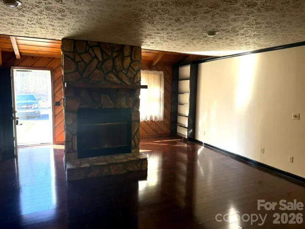a view of a living room with wooden floor fire place and a table