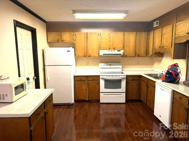 a kitchen with a sink a stove a refrigerator and wooden floor