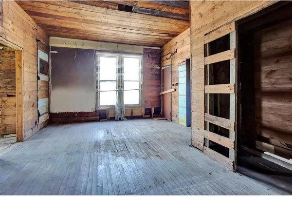 a view of an empty room with wooden floor and windows