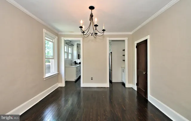 a view of an empty room with wooden floor and fan