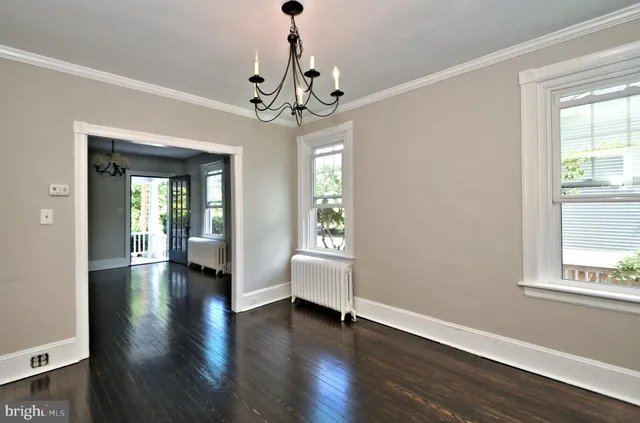 a view of an empty room with wooden floor fireplace and a window