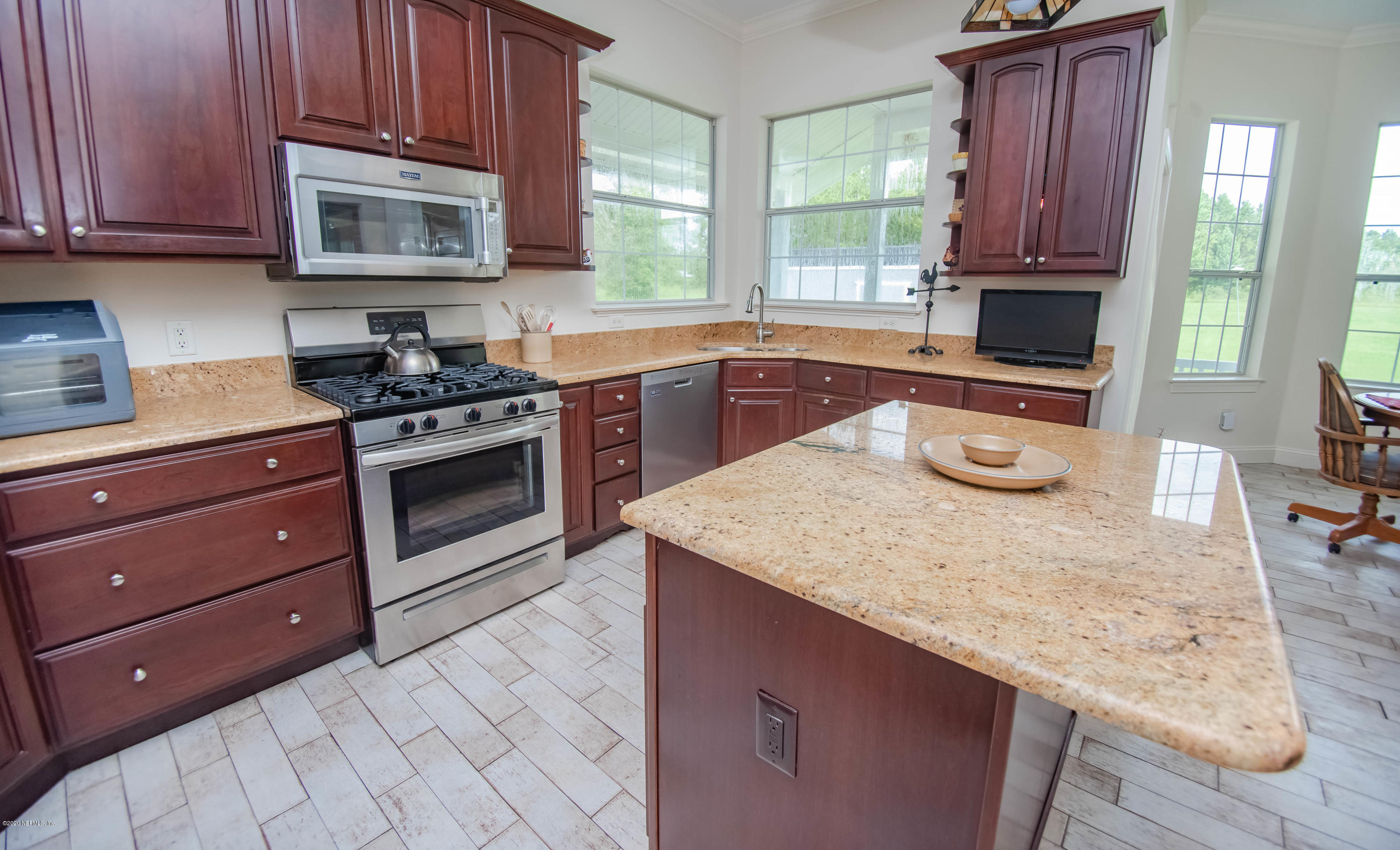 8219 Mud Lake Road Macclenny, FL 32063 - Photo 11 of 63 a kitchen with granite countertop wooden cabinets and a stove top oven