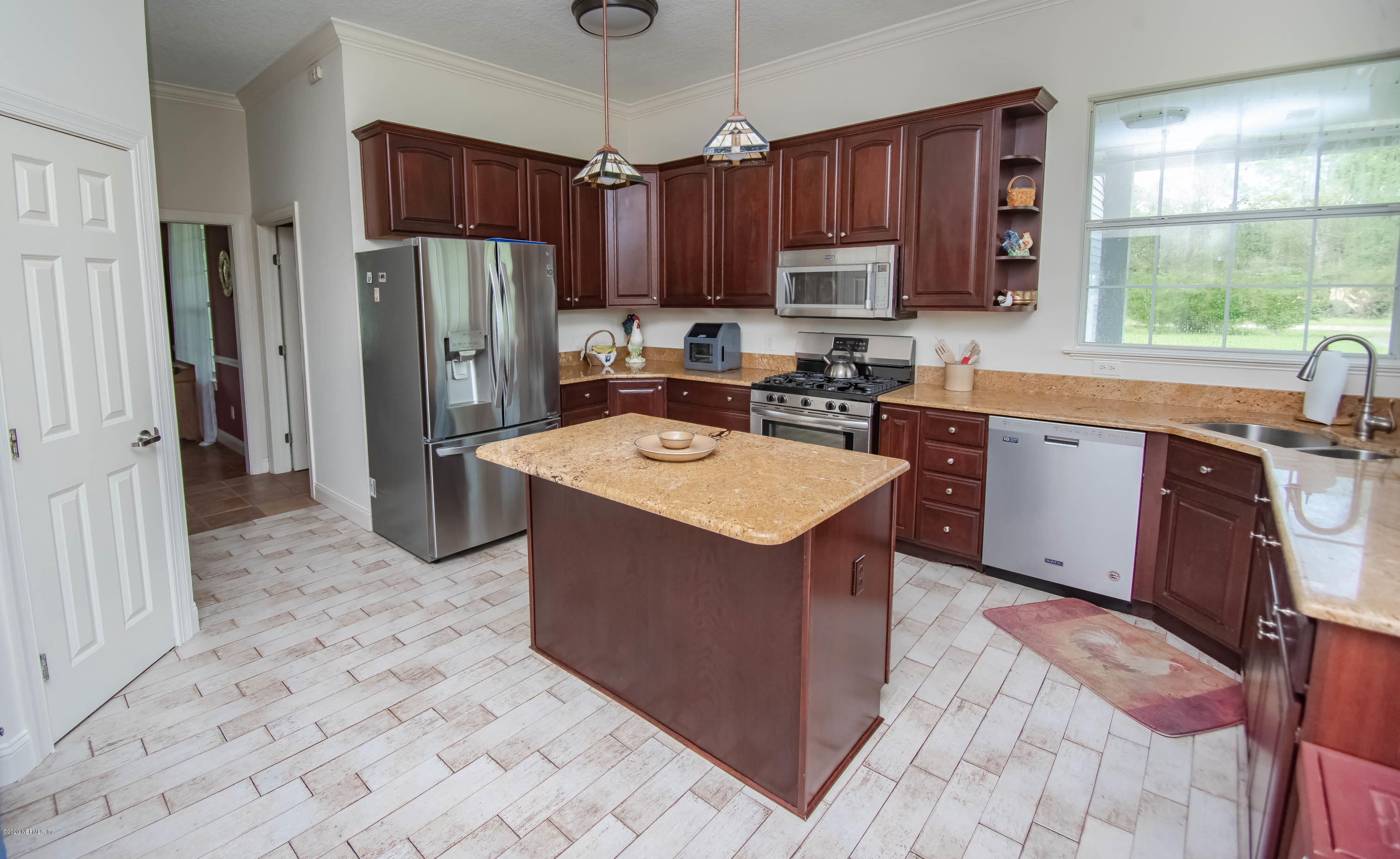 8219 Mud Lake Road Macclenny, FL 32063 - Photo 10 of 63 a kitchen with stainless steel appliances granite countertop a refrigerator a sink dishwasher a stove top oven a refrigerator and a dining table with wooden floor