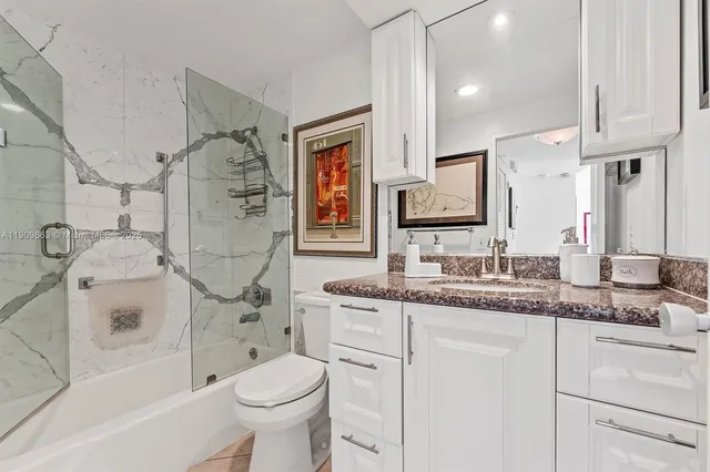 a bathroom with a granite countertop toilet sink and mirror
