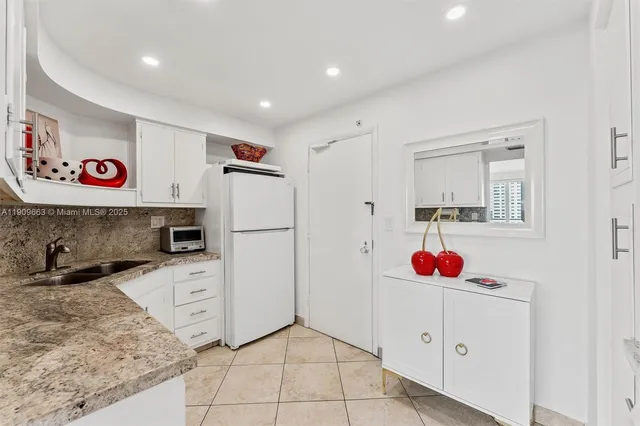 a view of kitchen with refrigerator and white cabinets