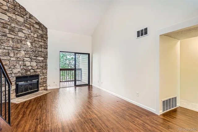 a view of an empty room with wooden floor fireplace and a window
