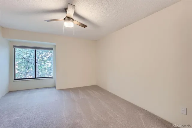 an empty room with windows and chandelier fan