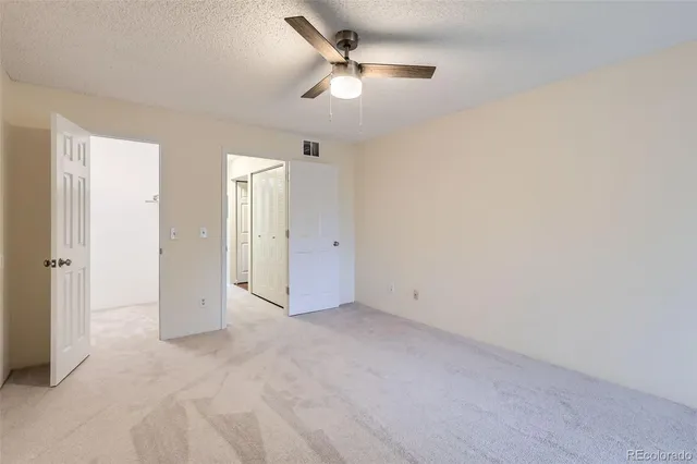 an empty room with ceiling fan and window