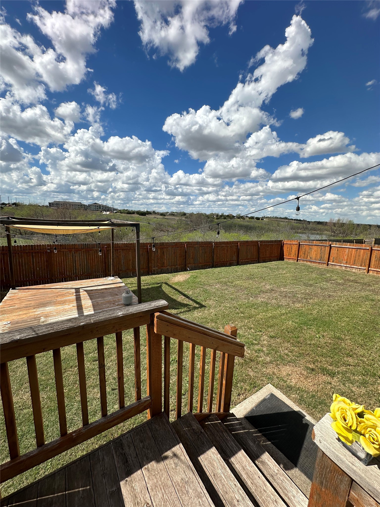 13000 Titanium Street Austin, TX 78754 - Photo 13 of 15 Expansive backyard featuring a large wood deck, lush green lawn, full perimeter wood fencing, and a separate shaded patio area