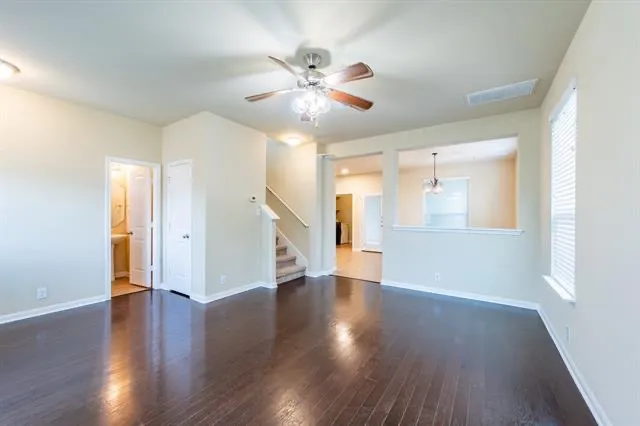 a view of an empty room with wooden floor and a ceiling fan