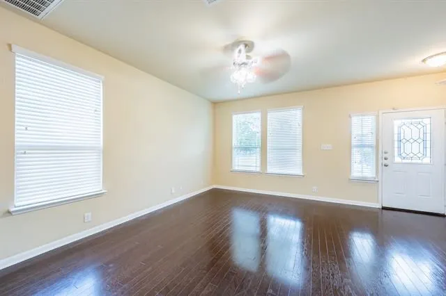a view of an empty room with wooden floor and a window