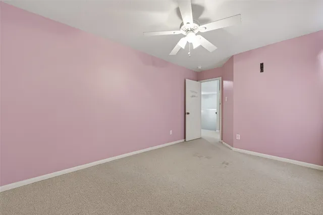 an empty room with a chandelier fan and windows