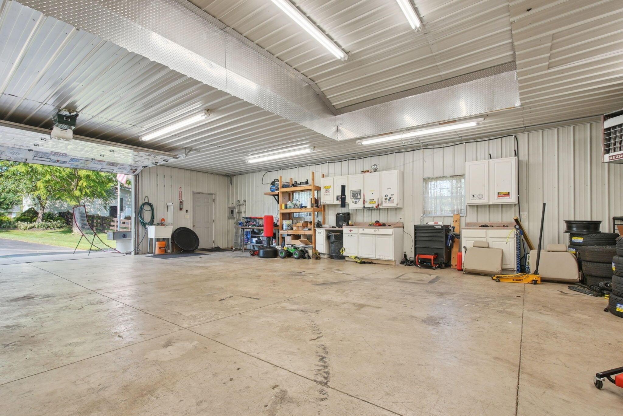 9435 Concord Road Powell, OH 43065 - Photo 53 of 77 Spacious heated garage featuring a concrete floor, corrugated metal walls, overhead lighting, and built-in cabinetry with countertops