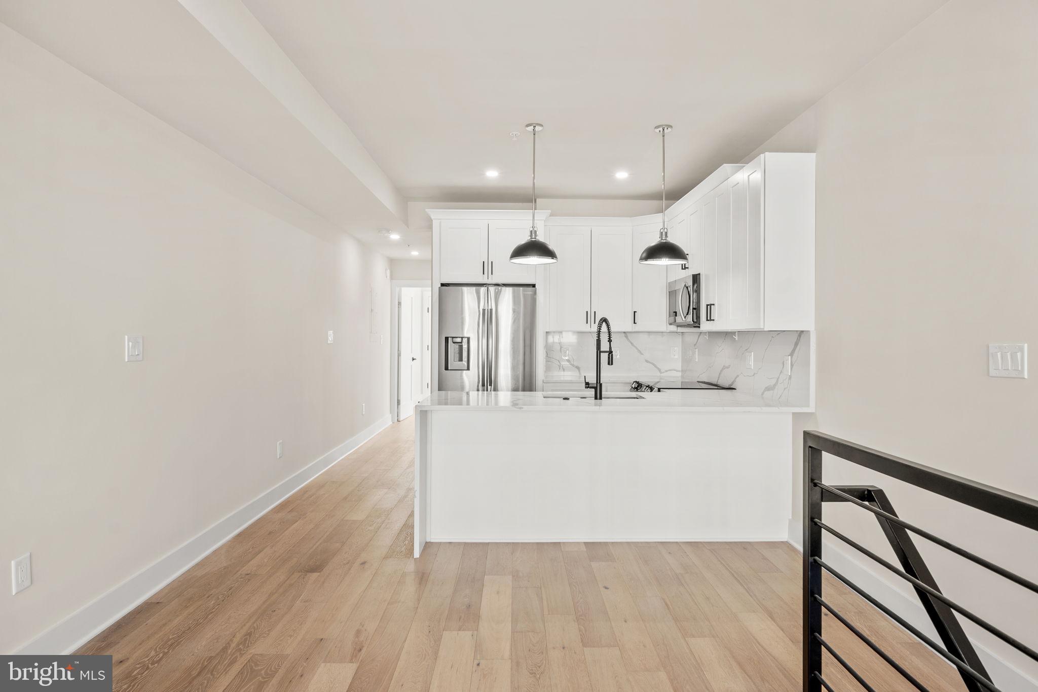 1923 Capitol Avenue Northeast, Unit 2 Washington, DC 20002 - Photo 6 of 32 a large white kitchen with wooden floors and white cabinets