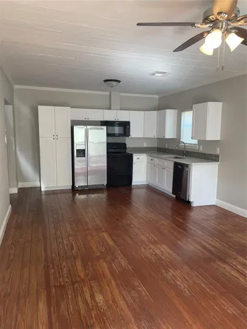 a kitchen with stainless steel appliances granite countertop a sink cabinets and wooden floor