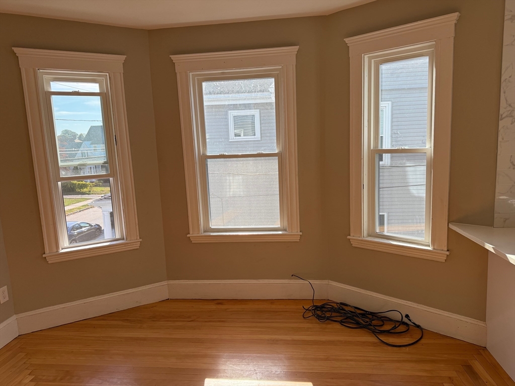 39 Rawson Road, Unit 2 Quincy, MA 02170 - Photo 2 of 6 a view of an empty room with wooden floor and a window
