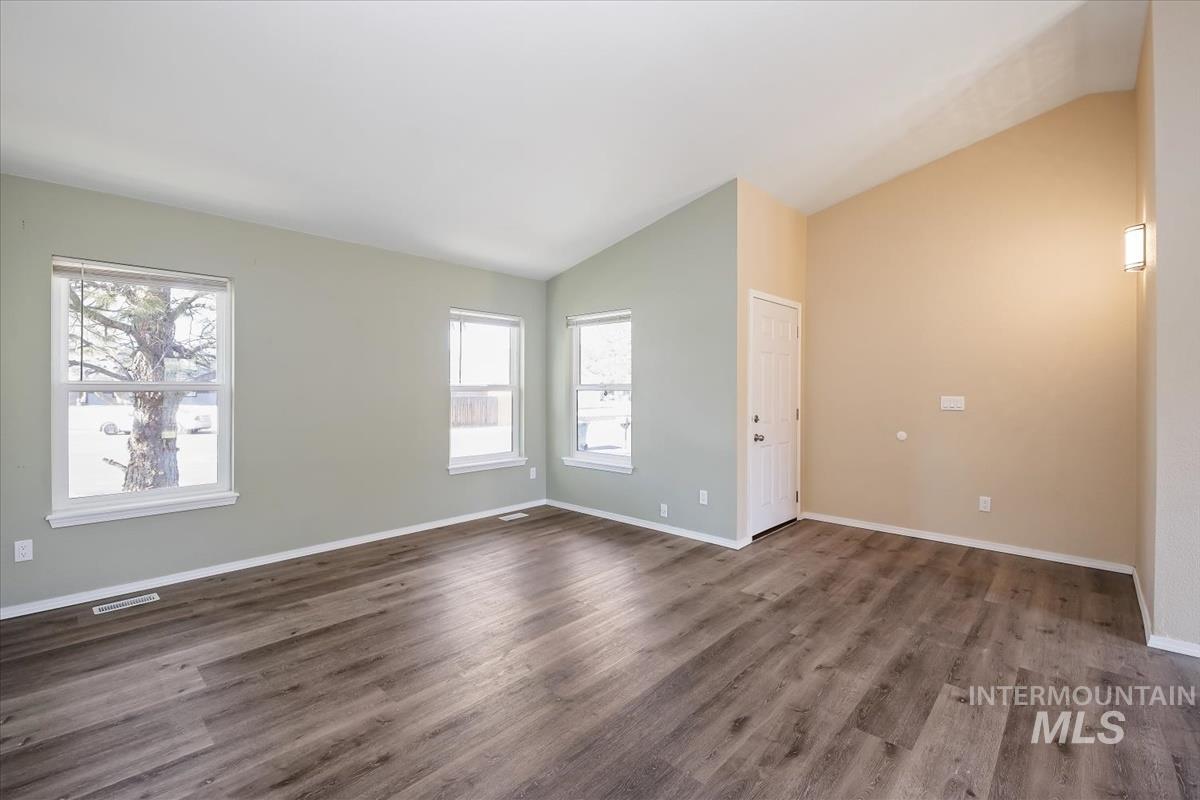 7091 West Limelight Street Boise, ID 83714 - Photo 6 of 34 Unfurnished room with vaulted ceiling and dark wood-style flooring