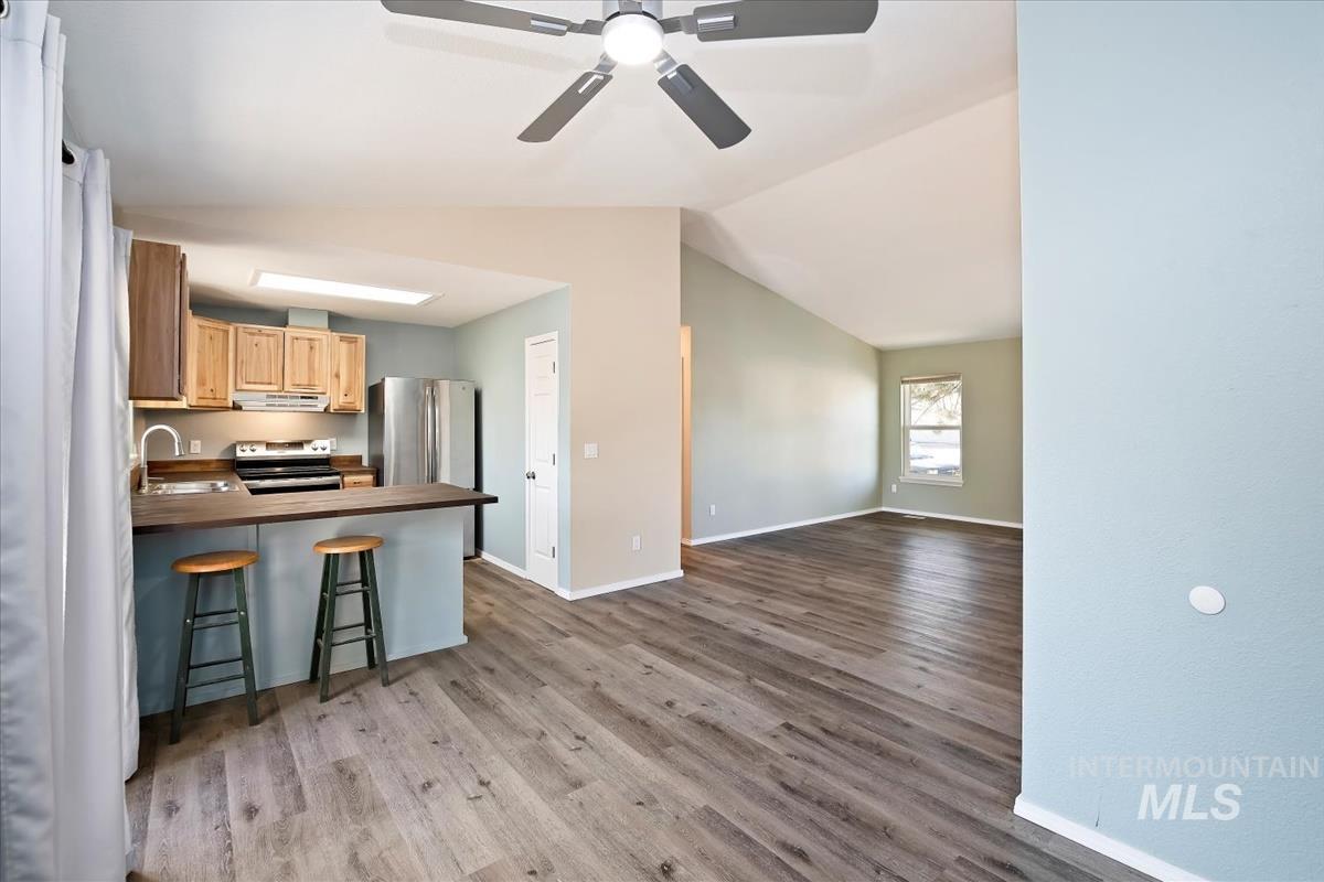 7091 West Limelight Street Boise, ID 83714 - Photo 8 of 34 Kitchen with a kitchen bar, a peninsula, stainless steel appliances, a ceiling fan, and light wood-type flooring