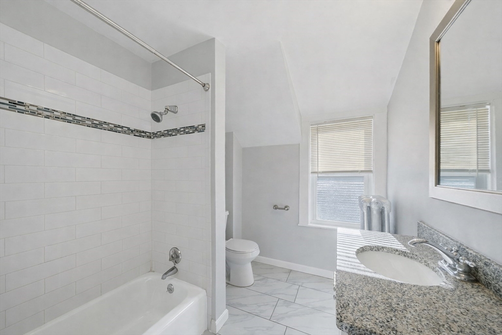 20 Wilson Street, Unit 2 Natick, MA 01760 - Photo 9 of 11 a bathroom with a granite countertop tub sink and mirror with bathtub