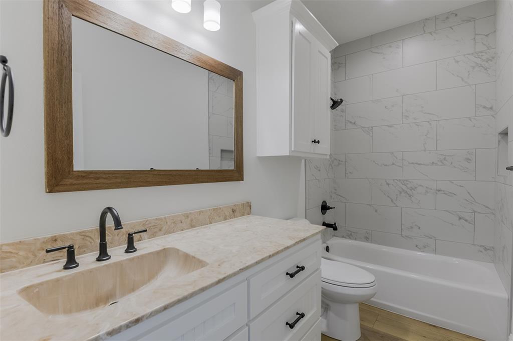 138 Zmolek Road Alma, TX 75119 - Photo 22 of 29 a bathroom with a granite countertop sink a toilet and bathtub