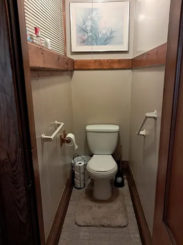 a bathroom with a toilet and a painting on the wall
