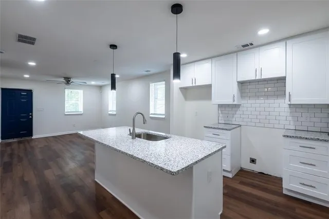 a kitchen with granite countertop kitchen island a sink appliances and a counter space