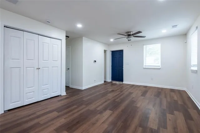 an empty room with wooden floor ceiling fan and windows