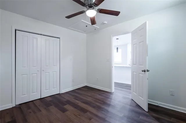 an empty room with wooden floor a ceiling fan and closet