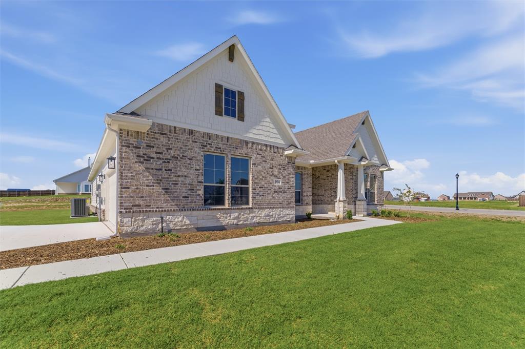 104 Snowy Owl Trail Rhome, TX 76078 - Photo 2 of 27 Contemporary exterior featuring a brick and stone facade, gabled rooflines, and a covered entry porch supported by substantial columns