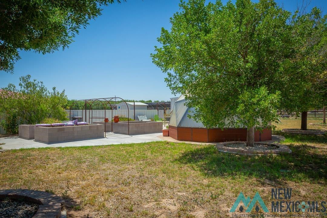 2012 South Haldeman Road Artesia, NM 88210 - Photo 79 of 96 Spacious backyard featuring a concrete patio, built-in raised garden beds, and a metal archway