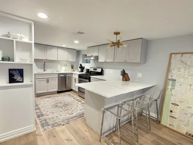 a kitchen with stainless steel appliances kitchen island granite countertop a sink a stove a refrigerator and a dining table with wooden floor