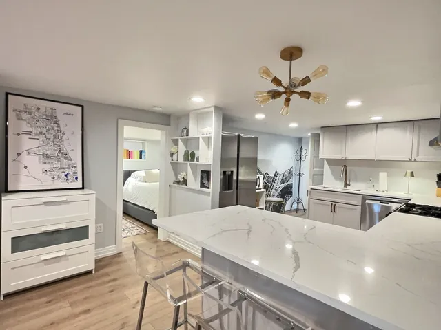 a view of a kitchen with kitchen island a stove a sink dishwasher a dining table and chairs with wooden floor