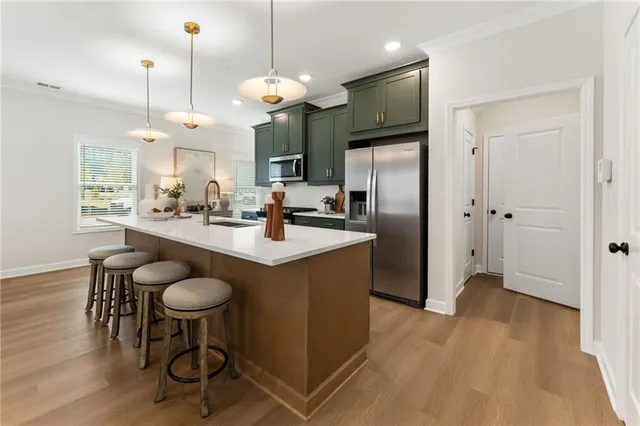 a kitchen with stainless steel appliances granite countertop a sink a refrigerator and a wooden floor