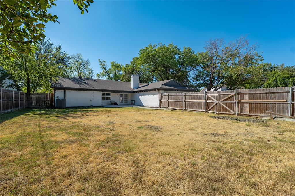 11005 Ferguson Road Dallas, TX 75228 - Photo 20 of 23 Expansive rear yard featuring a wood privacy fence, concrete patio, and mature trees