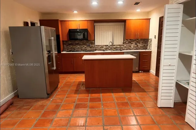 a kitchen with stainless steel appliances granite countertop a refrigerator a stove and a sink