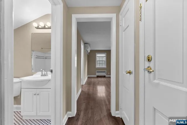 a view of a hallway with wooden floor windows and a bathroom