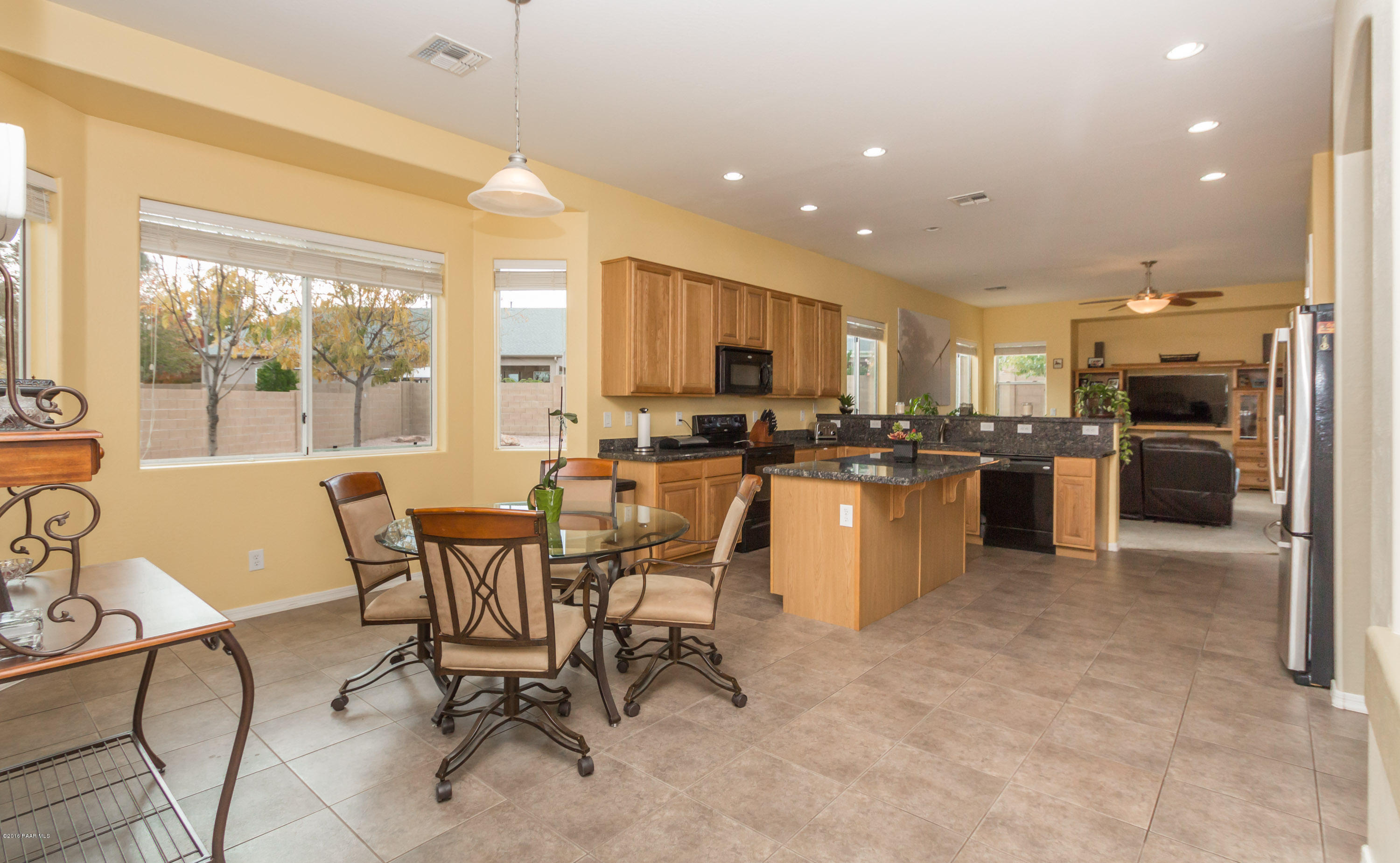 7887 East Mesteno Road Prescott Valley, AZ 86315 - Photo 10 of 30 a kitchen with stainless steel appliances kitchen island granite countertop a stove a sink a refrigerator a dining table and chairs