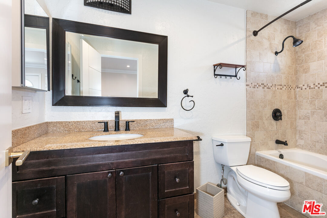 7001 Beckett Street Tujunga, CA 91042 - Photo 11 of 21 a bathroom with a granite countertop toilet sink and mirror