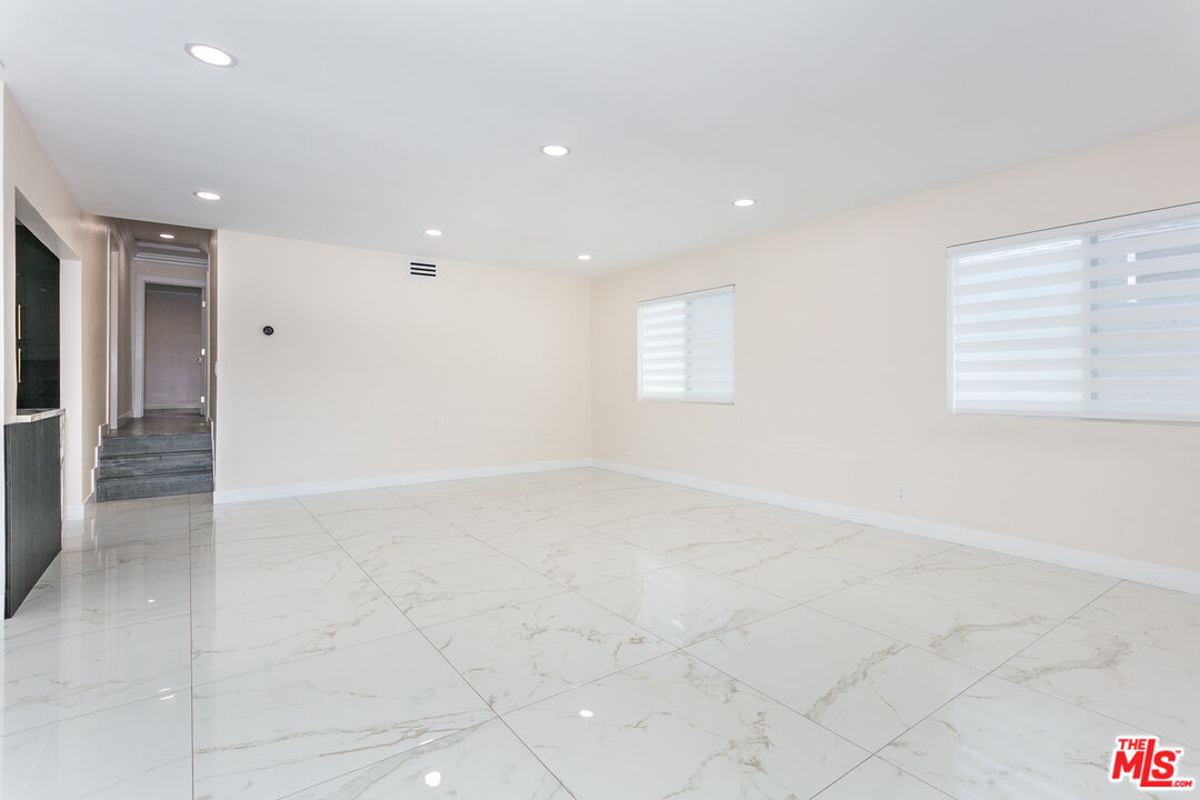 7001 Beckett Street Tujunga, CA 91042 - Photo 7 of 21 an empty room with windows and chandelier fan