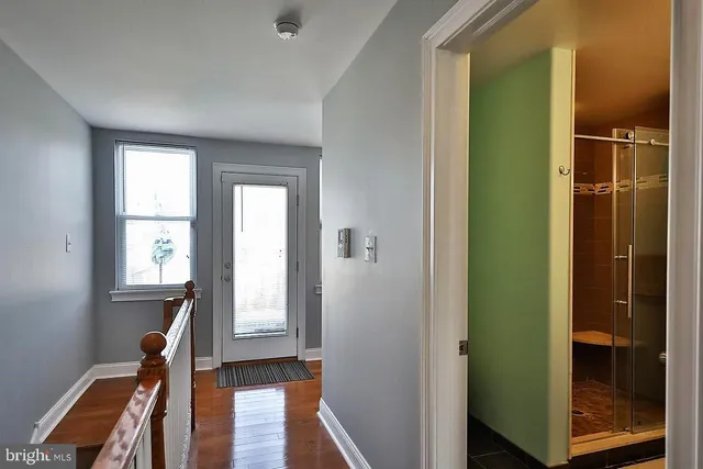 a view of a hallway with wooden floor and stairs
