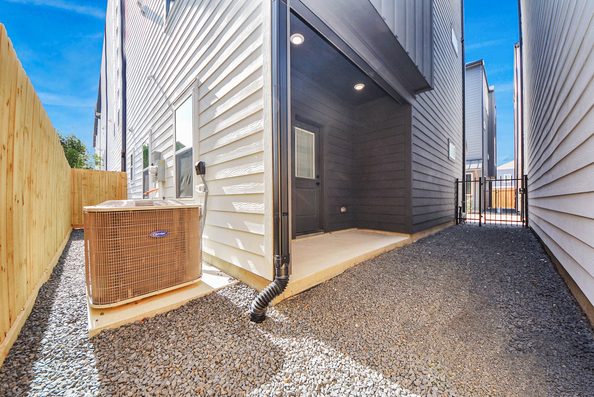 927 Fisher Street, Unit B Houston, TX 77018 - Photo 41 of 47 This functional side yard features gravel ground cover, a wooden fence, and an outdoor air conditioning unit. A gated entry provides secure access, making the space practical and well-maintained for utility needs.