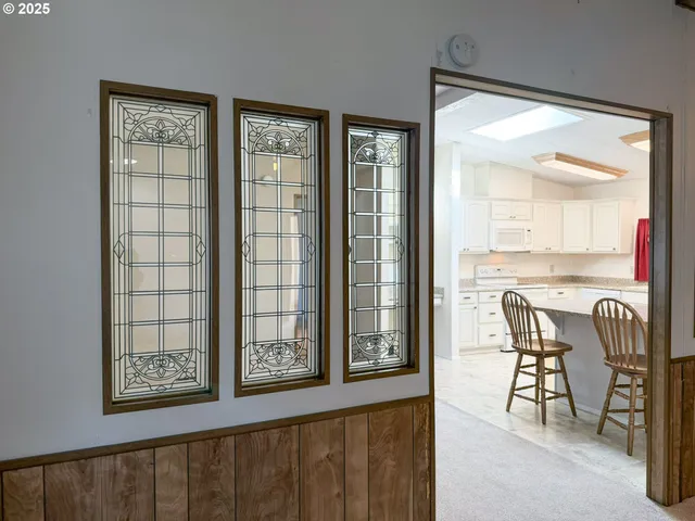 a kitchen with stainless steel appliances granite countertop a dining table chairs refrigerator and sink