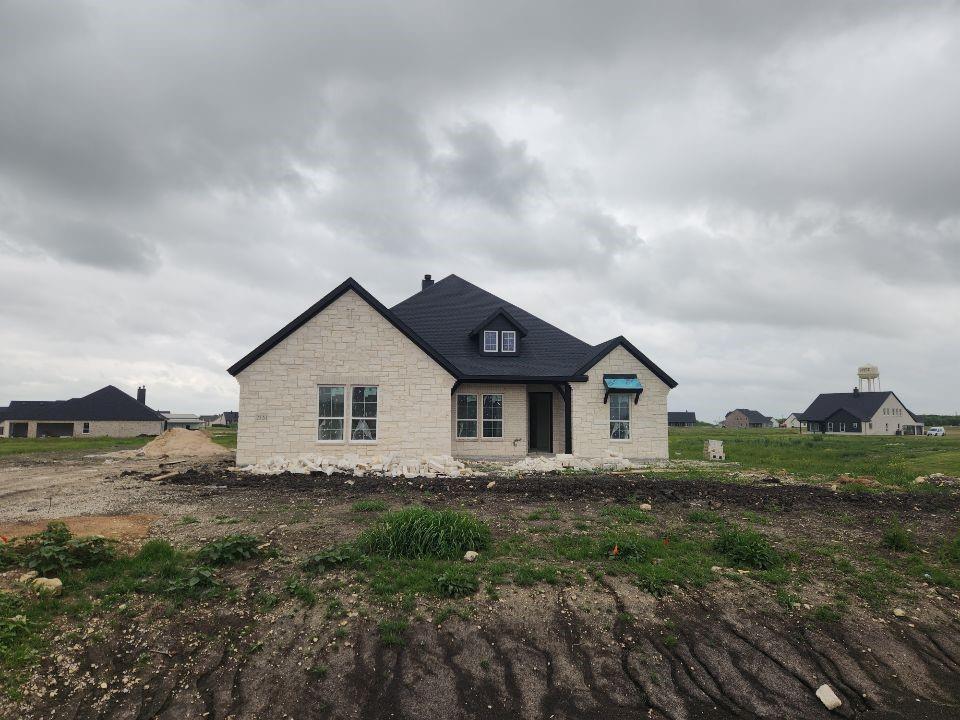 a view of house with a big yard and large trees