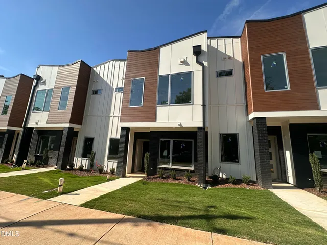 a view of a brick house with many windows and a yard