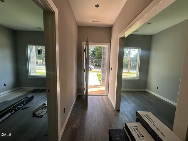 a view of a hallway with wooden floor and windows