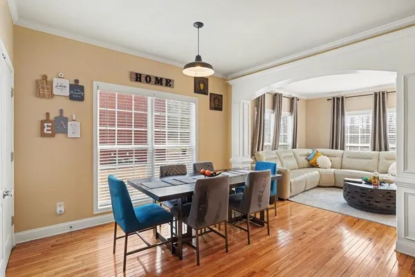 a dining room with wooden floor a chandelier a wooden table and chairs