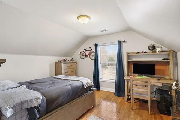 a bedroom with a bed and a flat tv screen on the dresser