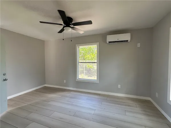 a view of an empty room with wooden floor and a window