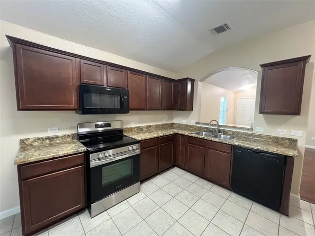 a kitchen with stainless steel appliances granite countertop a stove microwave and sink